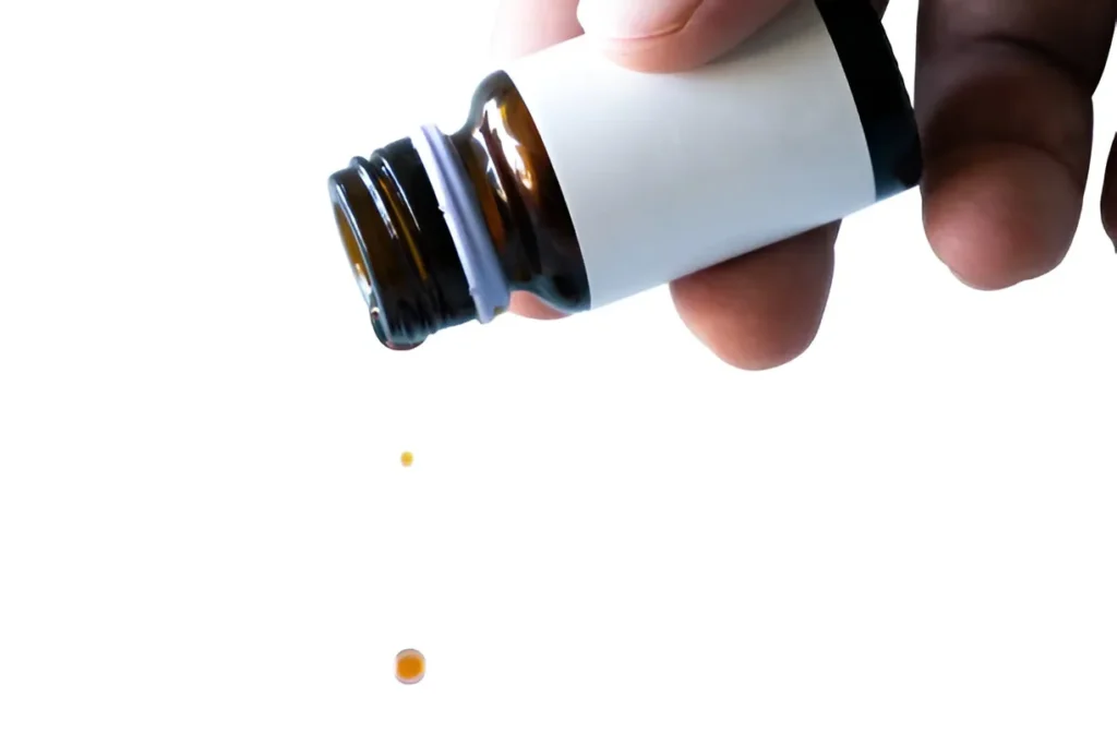 Hand holding a bottle of oral tirzepatide drops with visible liquid drops falling, used for weight loss and metabolic health support.
