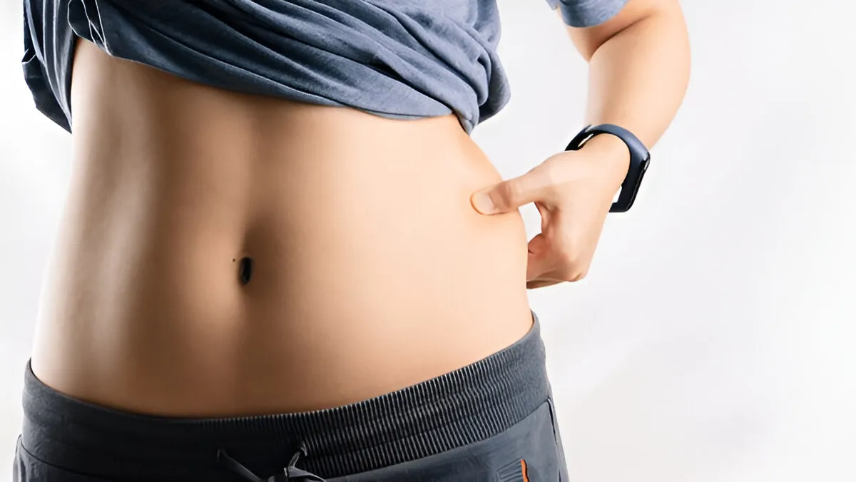 Woman checking belly fat reduction progress after using oral tirzepatide liquid drops for weight loss