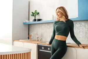 Fit woman standing confidently in kitchen after weight loss, showcasing successful oral tirzepatide results.