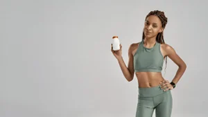 Fit young woman in activewear holding a supplement bottle, representing microdosing for energy and wellness.