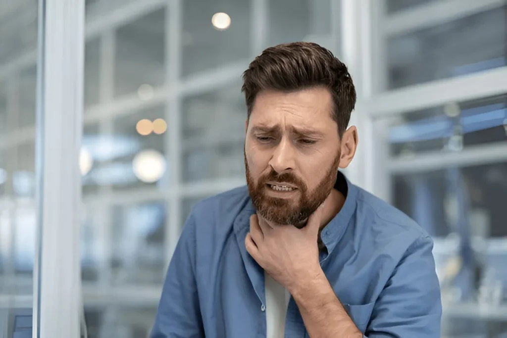 Man holding his throat in pain, showing symptoms of a sore throat or throat infection.